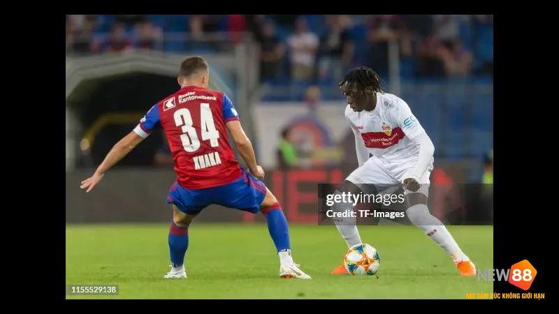 Cầu thủ Basel đi bóng qua cầu thủ Stuttgart trước sự chặn đứng của hậu vệ đối phương